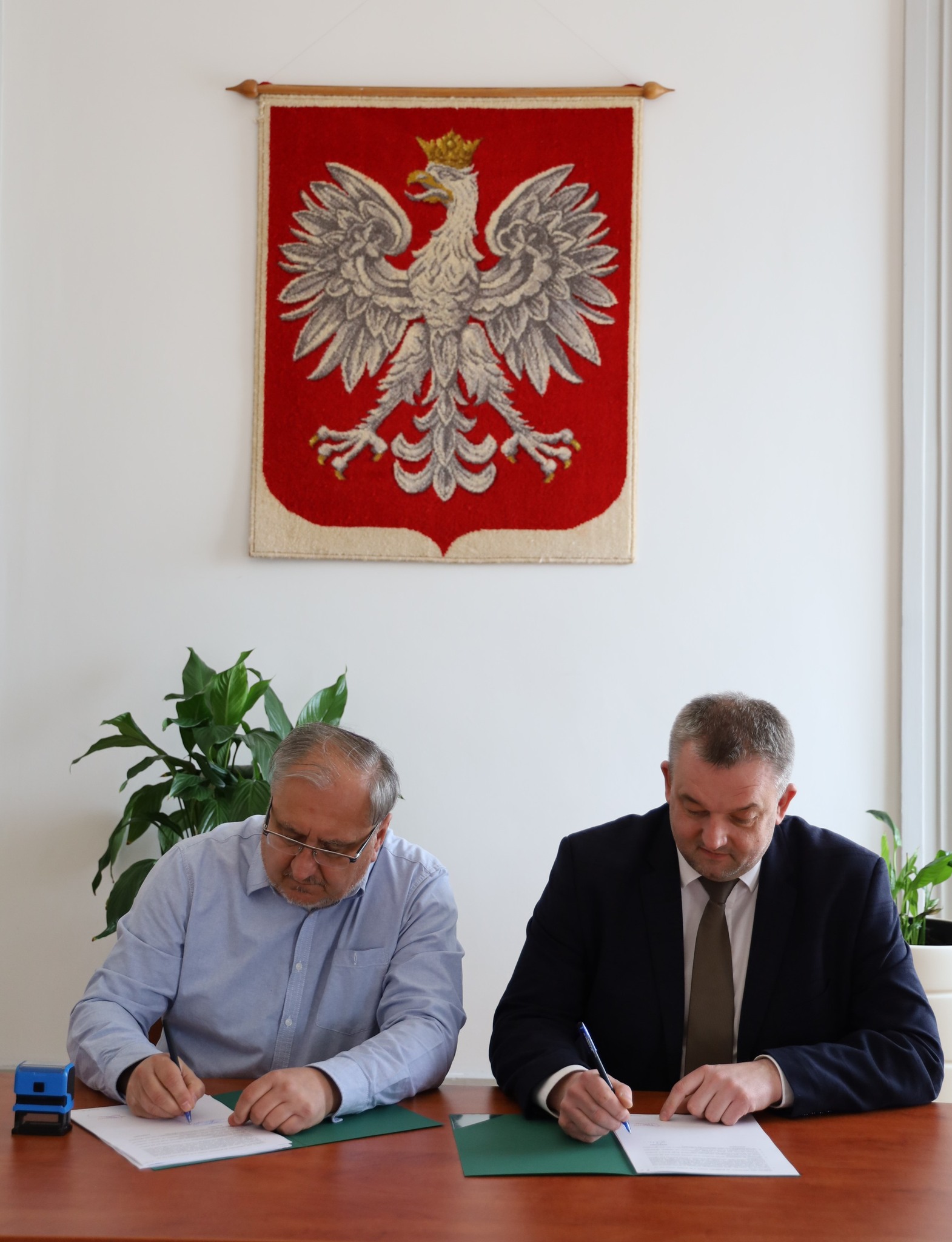 dwóch panów podpisuje kartkę